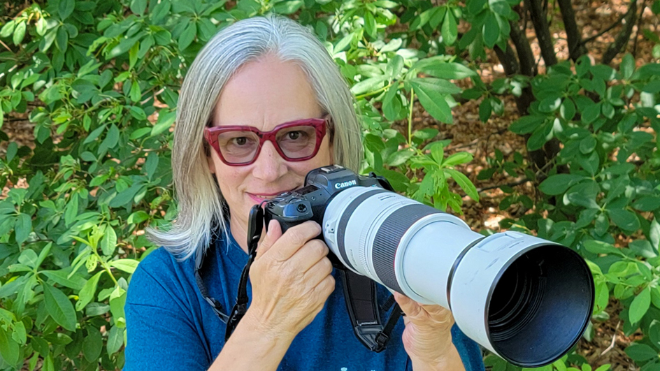 A woman peers over a camera