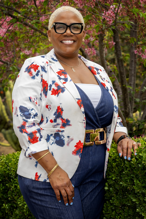 A smiling woman stands in a garden
