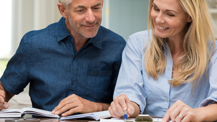A couple sits in their kitchen as they examine paperwork
