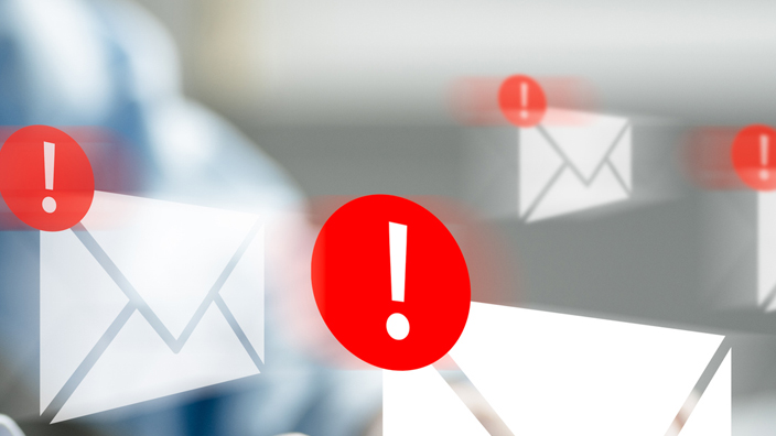 Hands typing on a laptop with illustrations of white envelopes and red warning notifications
