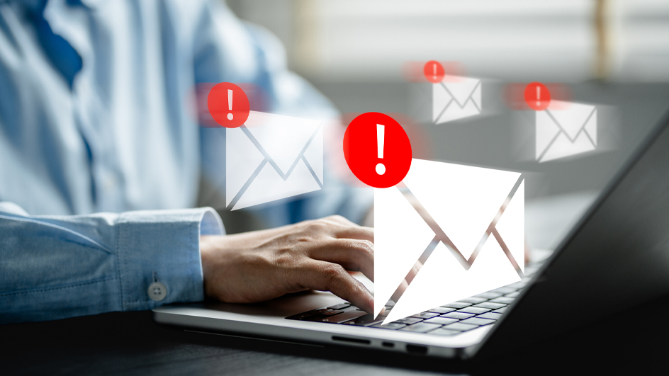 Hands typing on a laptop with illustrations of white envelopes and red warning notifications