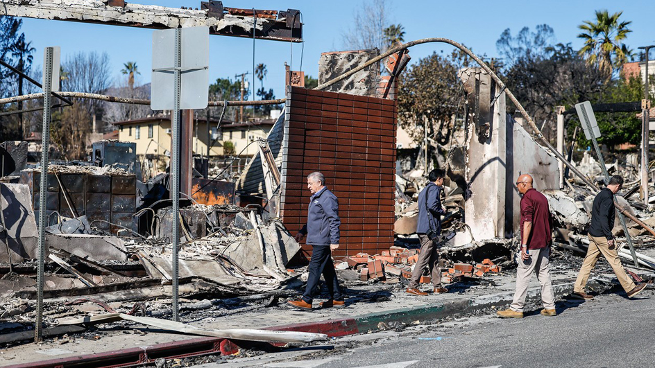 Four people outside of a burned-down building
