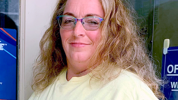 A woman stands near a bank of Post Office boxes