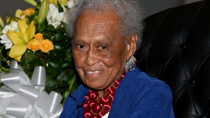 An older woman wearing blue sitting in a chair