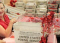 Three USPS employees sitting at a table stamping postmarks onto envelopes