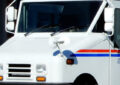 A USPS delivery vehicle is parked near a gas station pump
