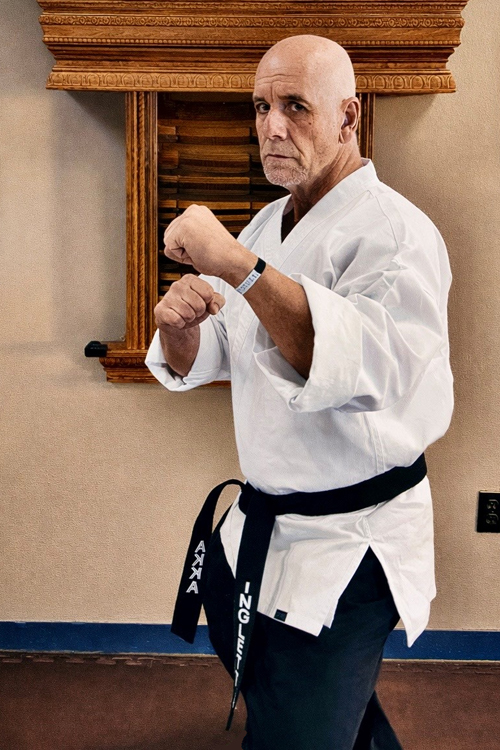Man in a fighting stance with fists raised wearing a martial arts uniform