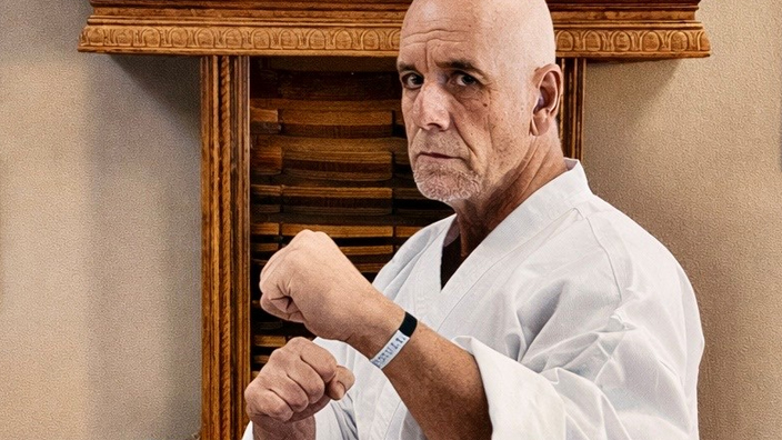 Man in a fighting stance with fists raised wearing a martial arts uniform