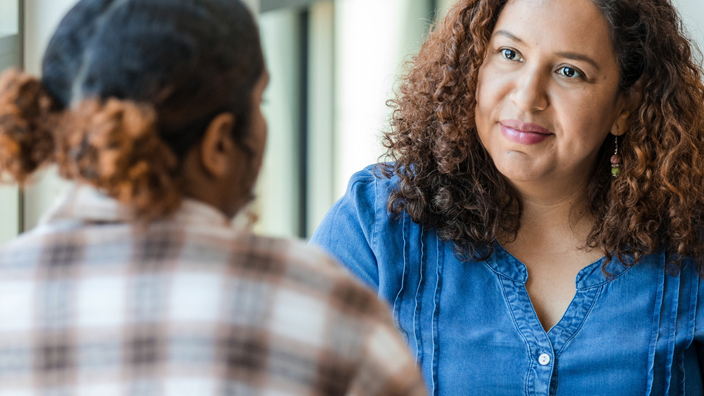 Two women in casual clothing having a discussion.
