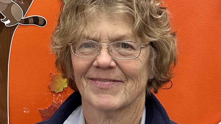A woman wearing a dark blue jacket with the USPS logo.