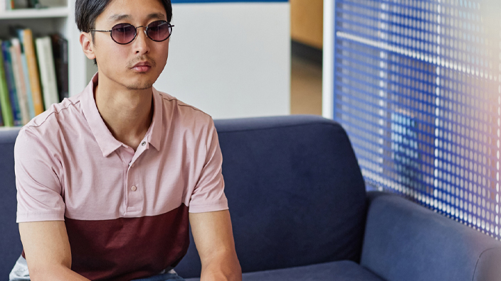 A man wearing dark glasses reading a book in tactile braille