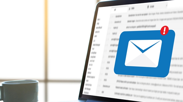 A laptop computer displaying blurred email and a blue notification icon
