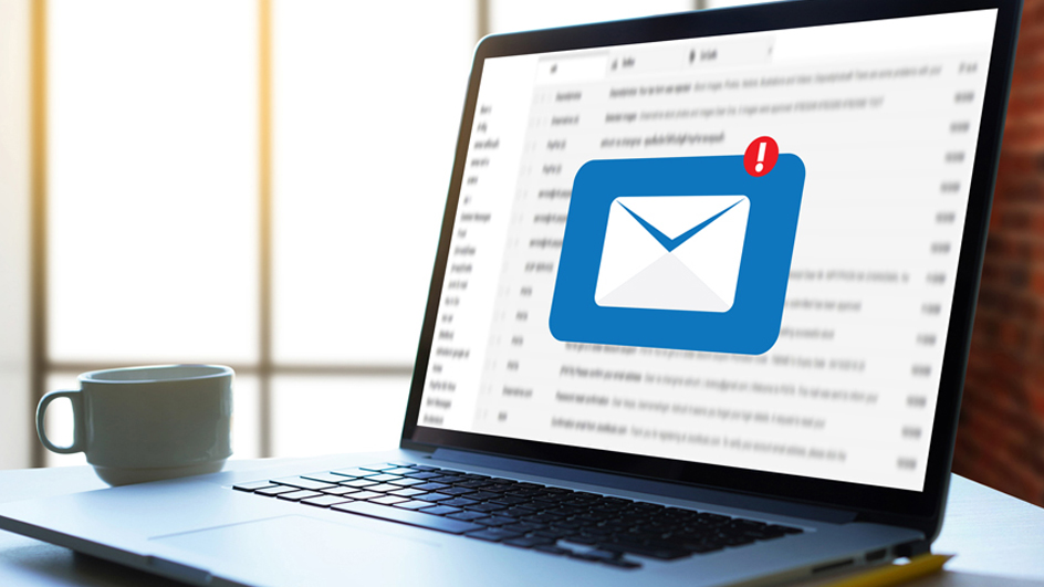A laptop computer displaying blurred email and a blue notification icon