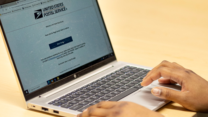 A laptop computer on a table showing the Postal Pulse survey on the screen