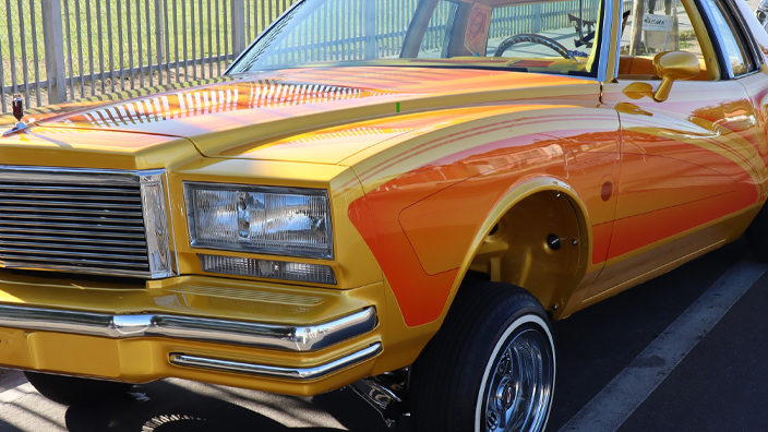 An orange-and-yellow Oldsmobile lowrider car