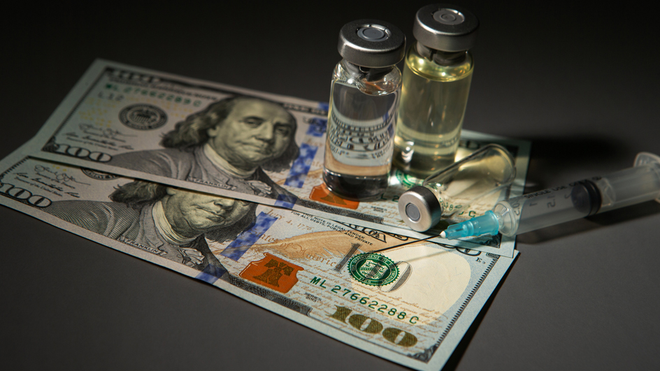 Three medical vials and a hypodermic needle laying on top of two $100 bills