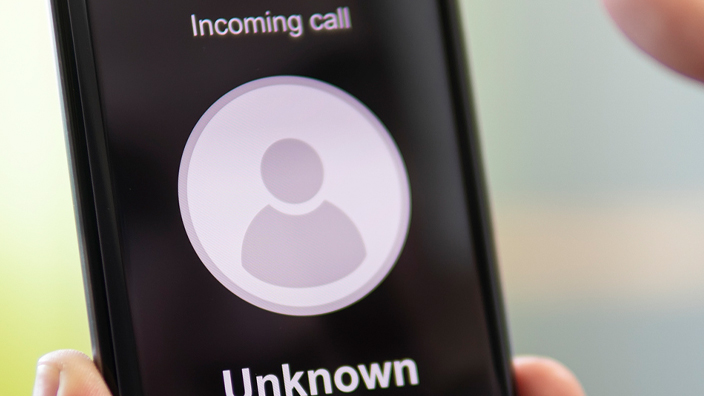 Person holding phone in hand displaying an incoming unknown call