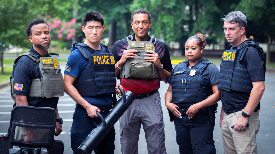 Group of uniformed postal inspectors standing outdoors wearing protective gear