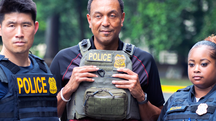 Group of uniformed postal inspectors standing outdoors wearing protective gear