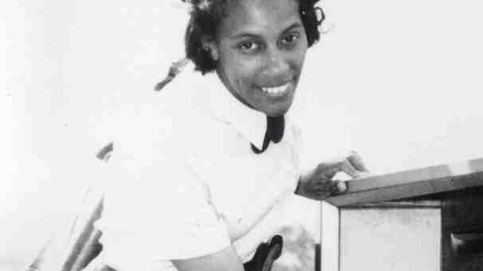 Black-and-white photo of a female postal worker placing mail into a U.S. Mail collection box