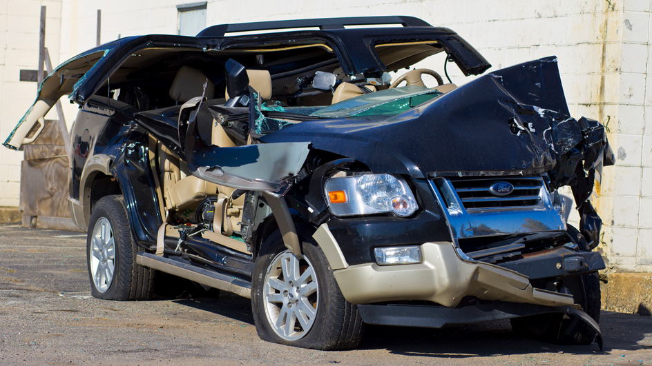 Damaged SUV with severe front and side impact, parked beside a building