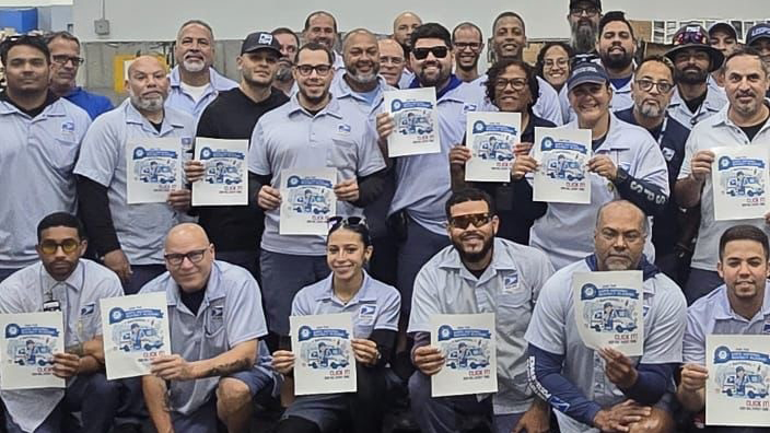 A large group of USPS employees, each one posing with a seat belt pledge poster