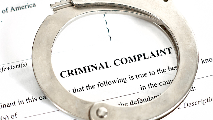 Handcuffs resting on a criminal complaint form from a U.S. District Court