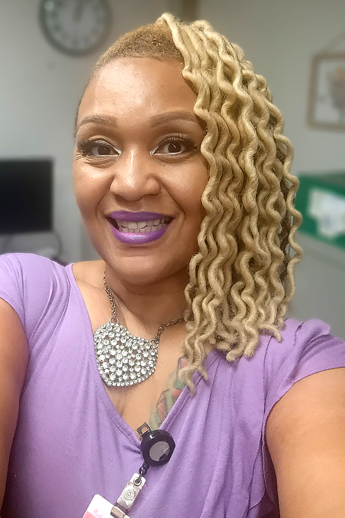 USPS employee wearing a lavender blouse and large heart-shaped necklace