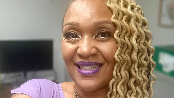 USPS employee wearing a lavender blouse and large heart-shaped necklace