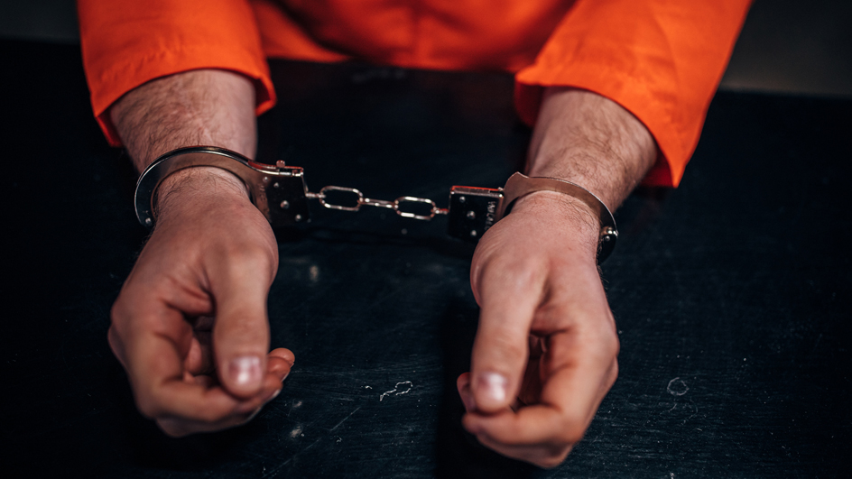 A pair of handcuffed hands resting on a table
