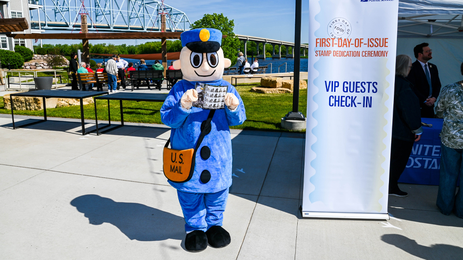 Mr. ZIP mascot wearing a blue letter carrier costume with a mail satchel and holding up a set of Bald Eagle: Hatchling to Adult stamps.