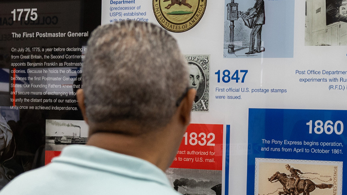 Man looking at a display showing a timeline of USPS history