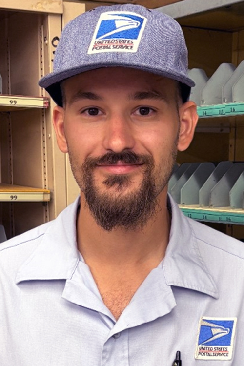 USPS employee wearing a light blue button-up shirt and a blue hat