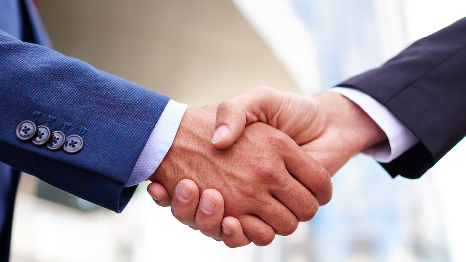 Close-up of a handshake between two people wearing suits