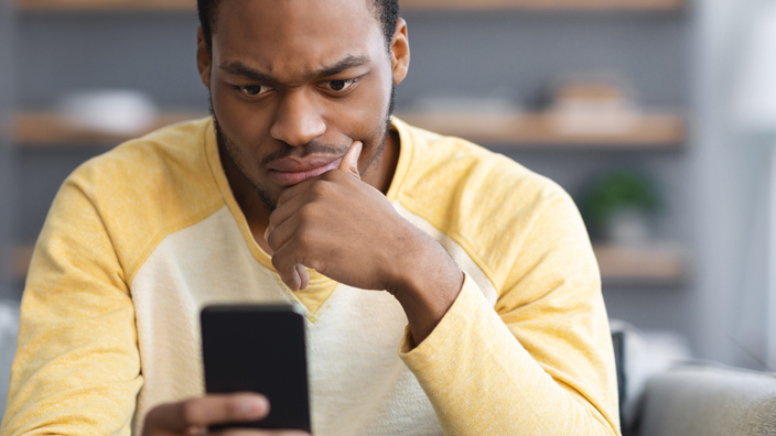 A man in a yellow shirt looking at his cell phone