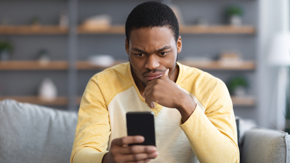 A man in a yellow shirt looking at his cell phone