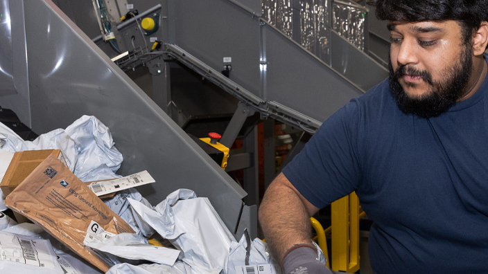 USPS employee handling mail in a sorting facility