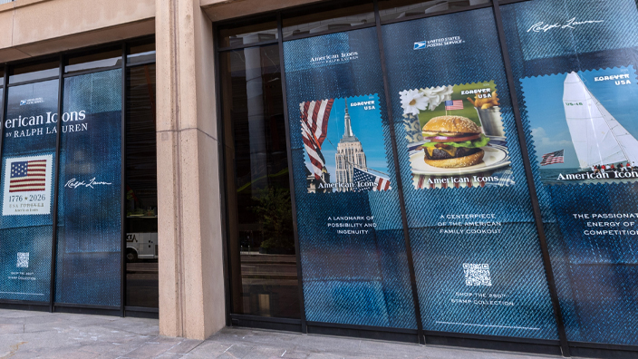 Outside of the USPS headquarters building with large window decals showing images of the American Icons stamps