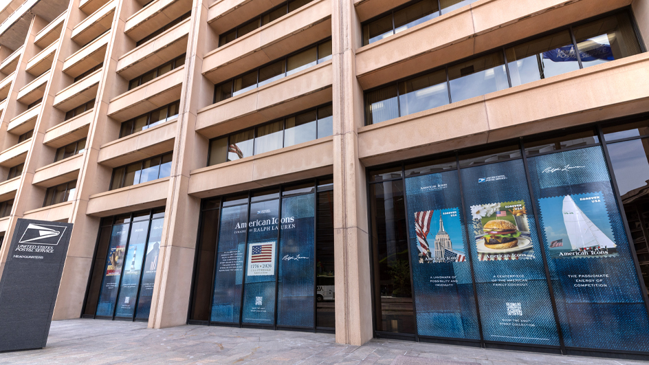 Outside of the USPS headquarters building with large window decals showing images of the American Icons stamps