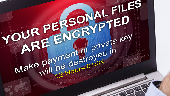 A person staring down at a laptop screen displaying a ransomware message