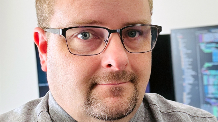 Man wearing glasses and a gray button-up shirt