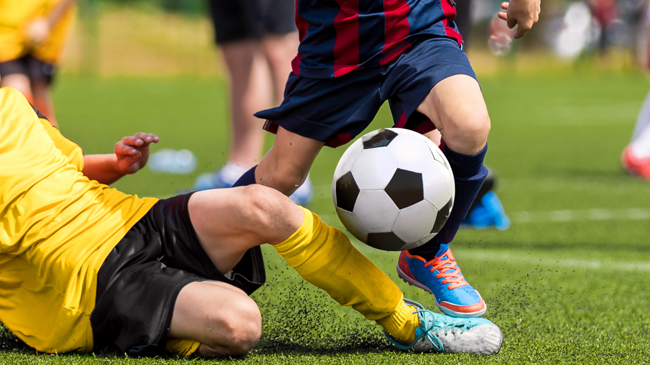 Young boys playing soccer on a grass field