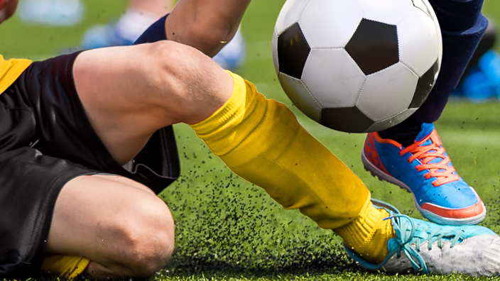 Young boys playing soccer on a grass field