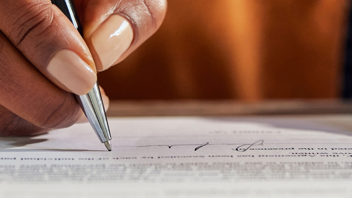 Close up of a woman’s hands signing documents