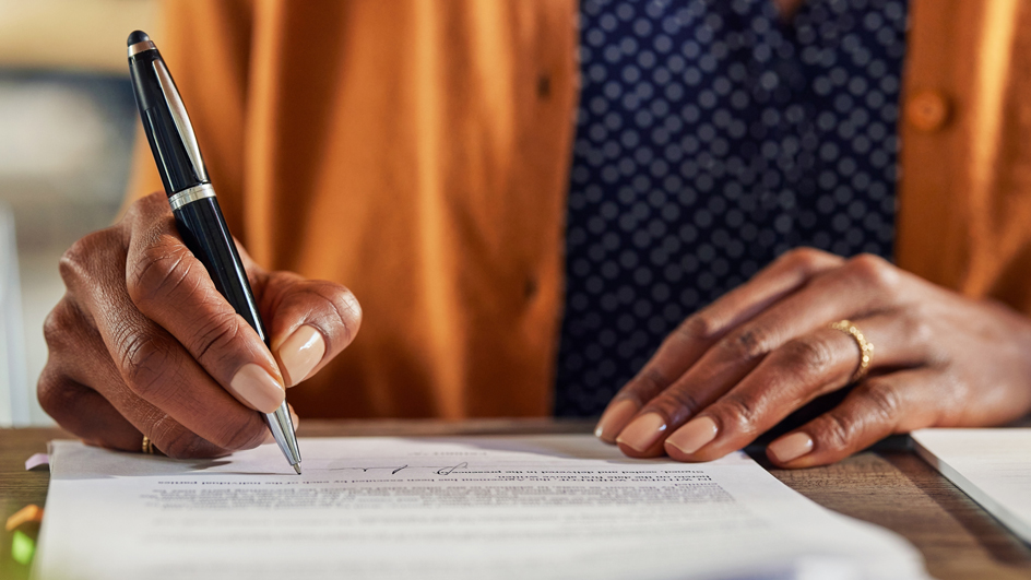 Close up of a woman’s hands signing documents