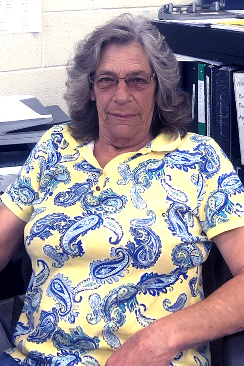 A seated woman wearing a yellow and blue paisley shirt