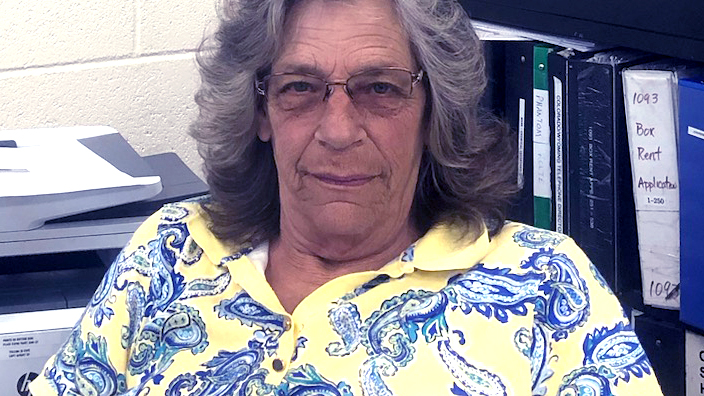A seated woman wearing a yellow and blue paisley shirt