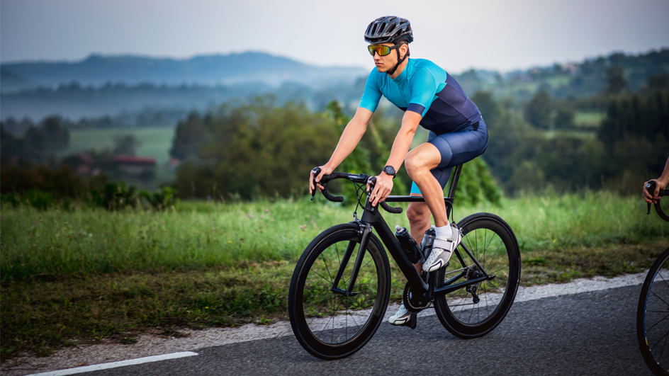 Man in a blue cycling uniform riding a bike through a countryside