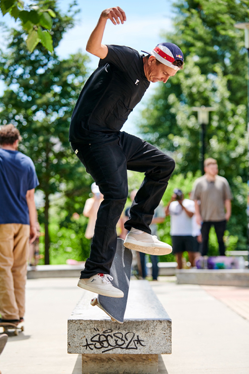 A man wearing dark clothes performing a skateboard trick