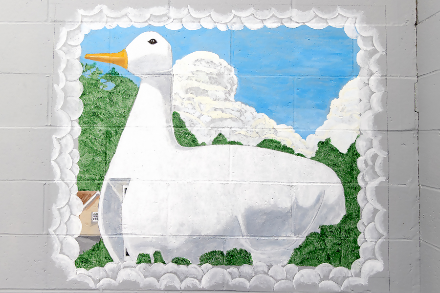 Painted mural of a building in the shape of a large, white duck